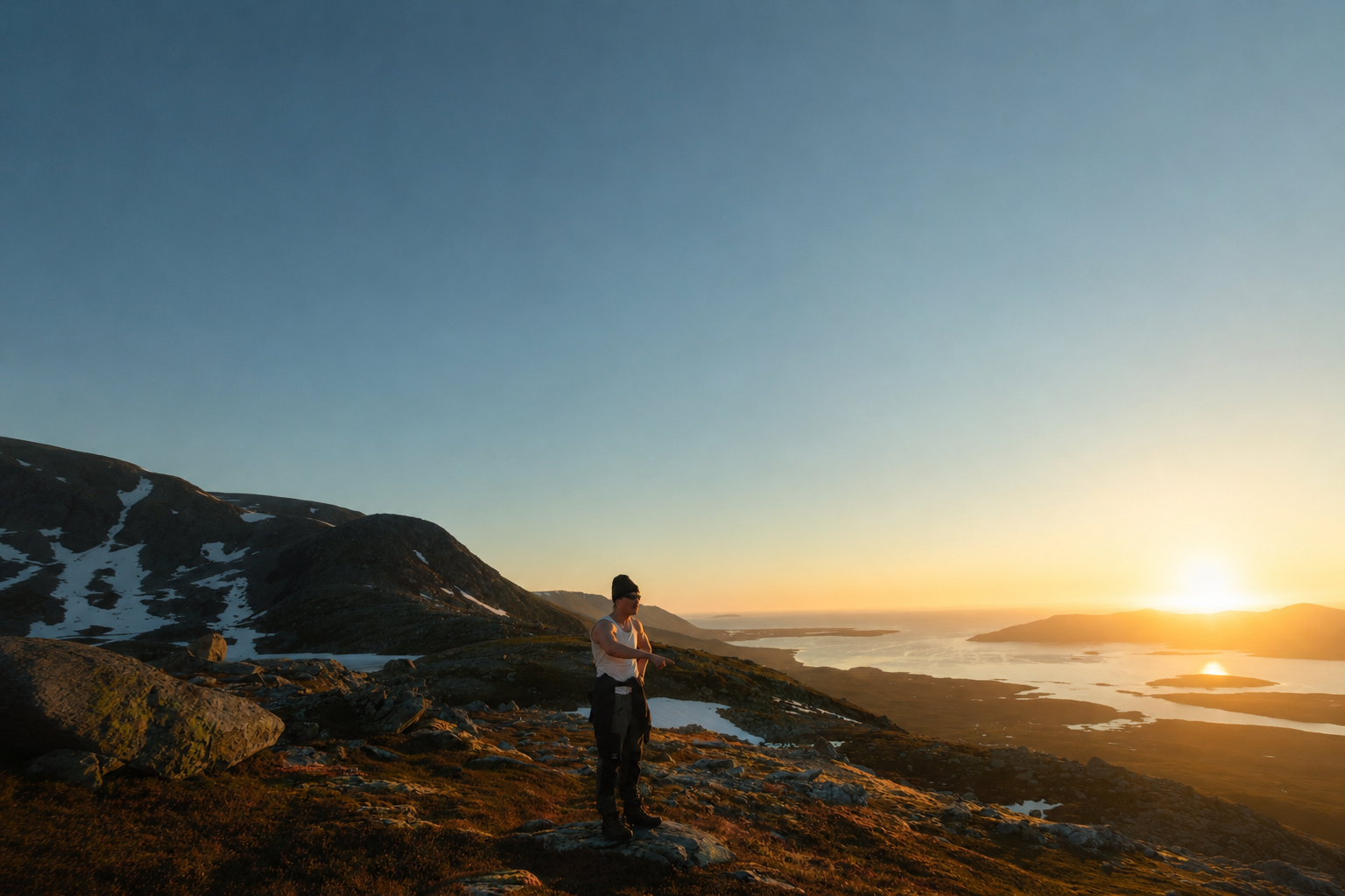 Ole på et fjell i gyllen kveldssol med utsikt mot kysten